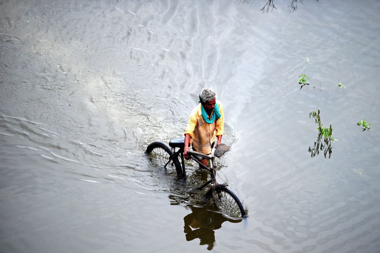 A resident pushes his bicycle through floodwaters in Allahabad, India, on August 29. Many areas in the northern Indian state of Uttar Pradesh are inundated from prolonged monsoon rains.