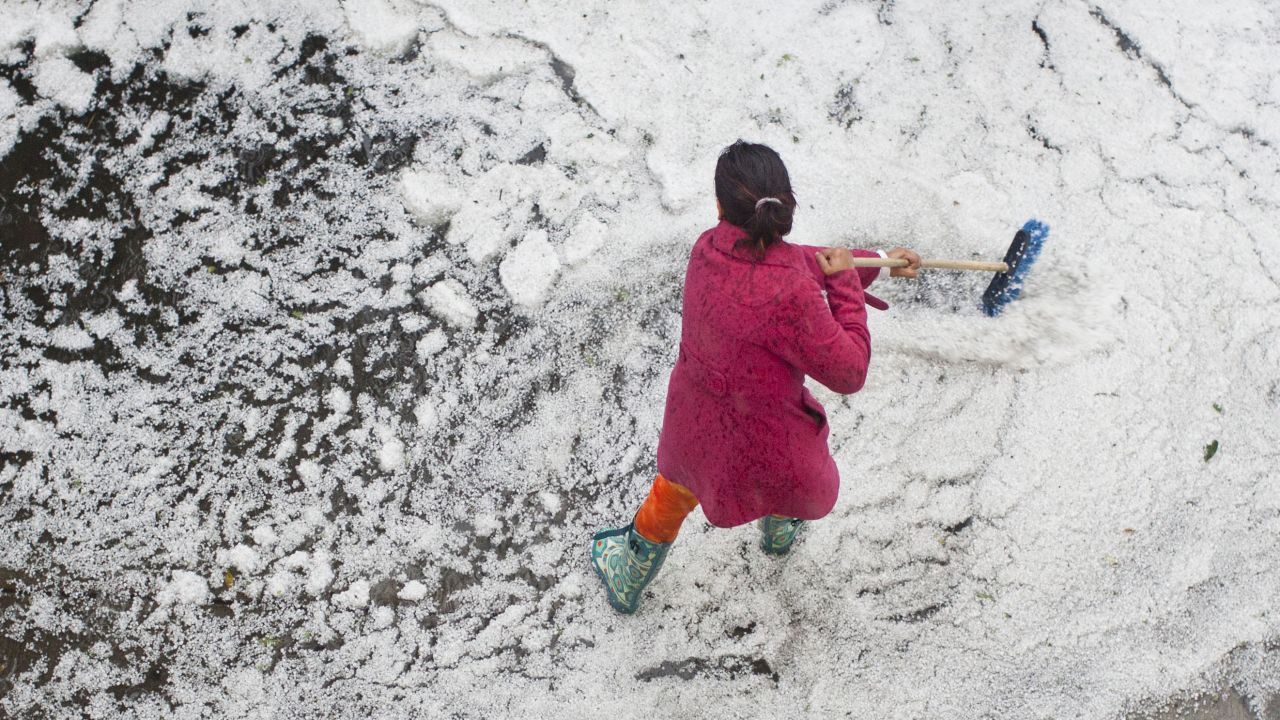 A woman sweeps hail off of a sidewalk in front of her home after a storm dumped hail on parts of Mexico City on Saturday, August 31. Click through to see other images of weather around the world.