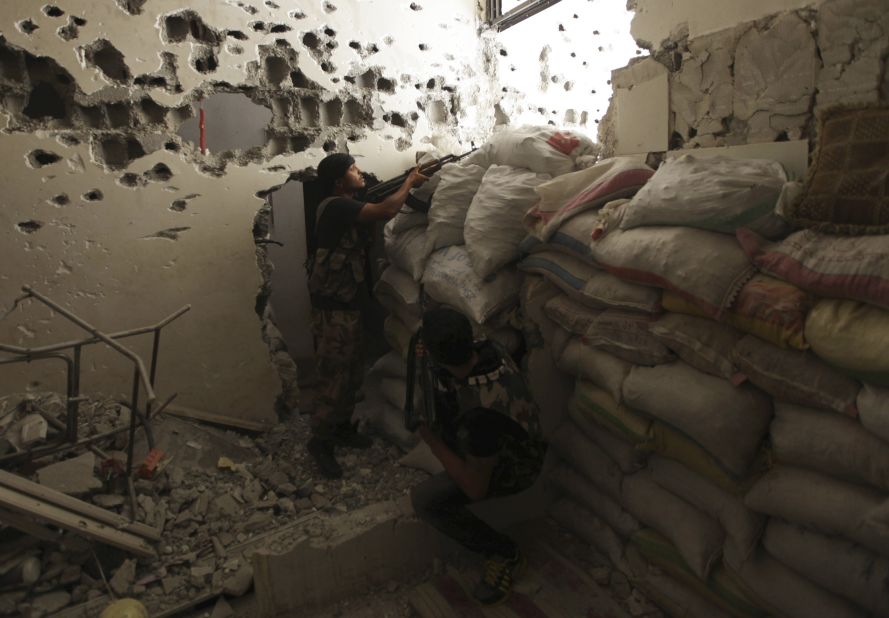 Free Syrian Army fighters take their positions behind piled sandbags, as one of them points his weapon, in Deir ez-Zor on September 2.