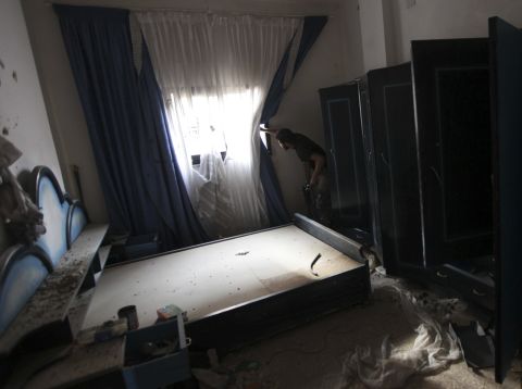 A Free Syrian Army fighter peeks through the curtains of a bedroom in Deir ez-Zor, Syria, on Monday, September 2.