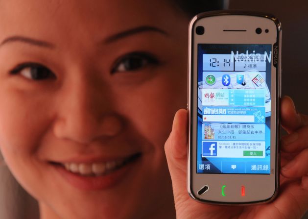 A sales assistant holds up a Nokia handset featuring a new mobile internet music download platform at a store in Hong Kong on June 18, 2009.