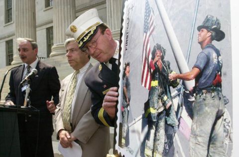 The stamp is displayed at a ceremony outside of the Brooklyn Borough Hall in New York on July 2, 2002. From left, Brooklyn Postmaster Joseph Lubrano, Borough President Marty Markowitz and Harold Meyers of the New York City Fire Department were in attendance.