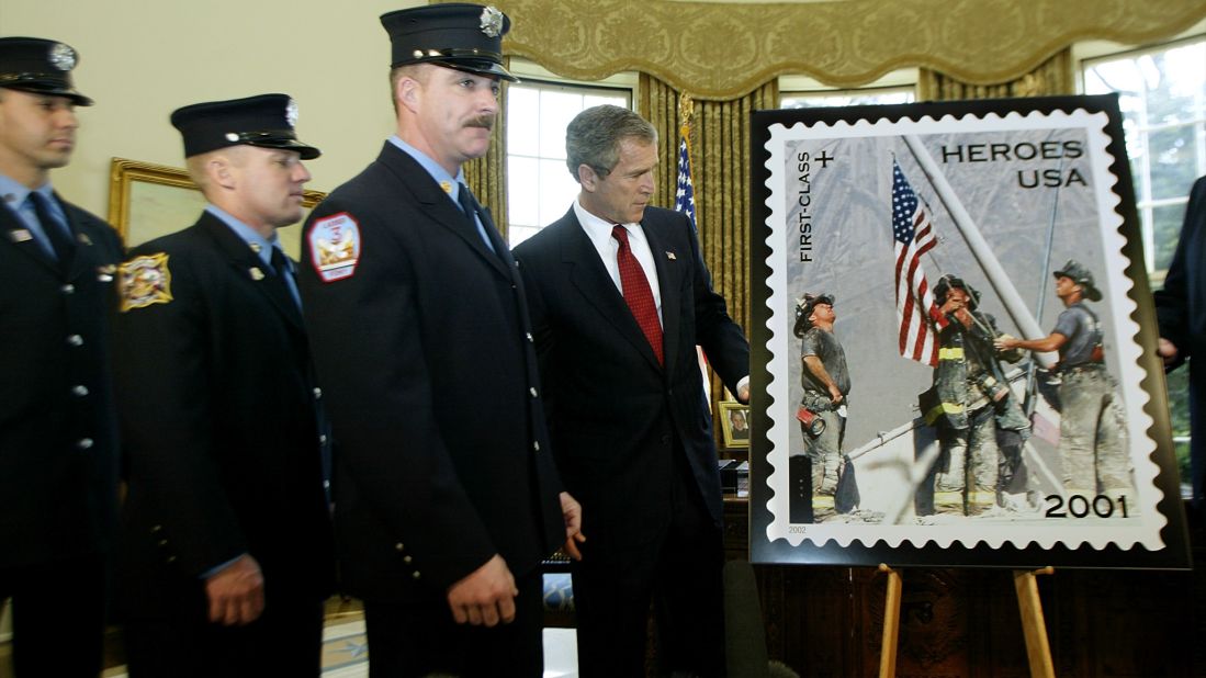 President George W. Bush unveils a "Heroes of 2001" stamp issued by the Postal Service on March 11, 2002, to raise funds to assist the families of emergency relief workers killed or permanently disabled as a result of the World Trade Center attacks. He is joined at the White House by the firefighters who are featured in the image, from left, Eisengrein, Johnson and McWilliams. 