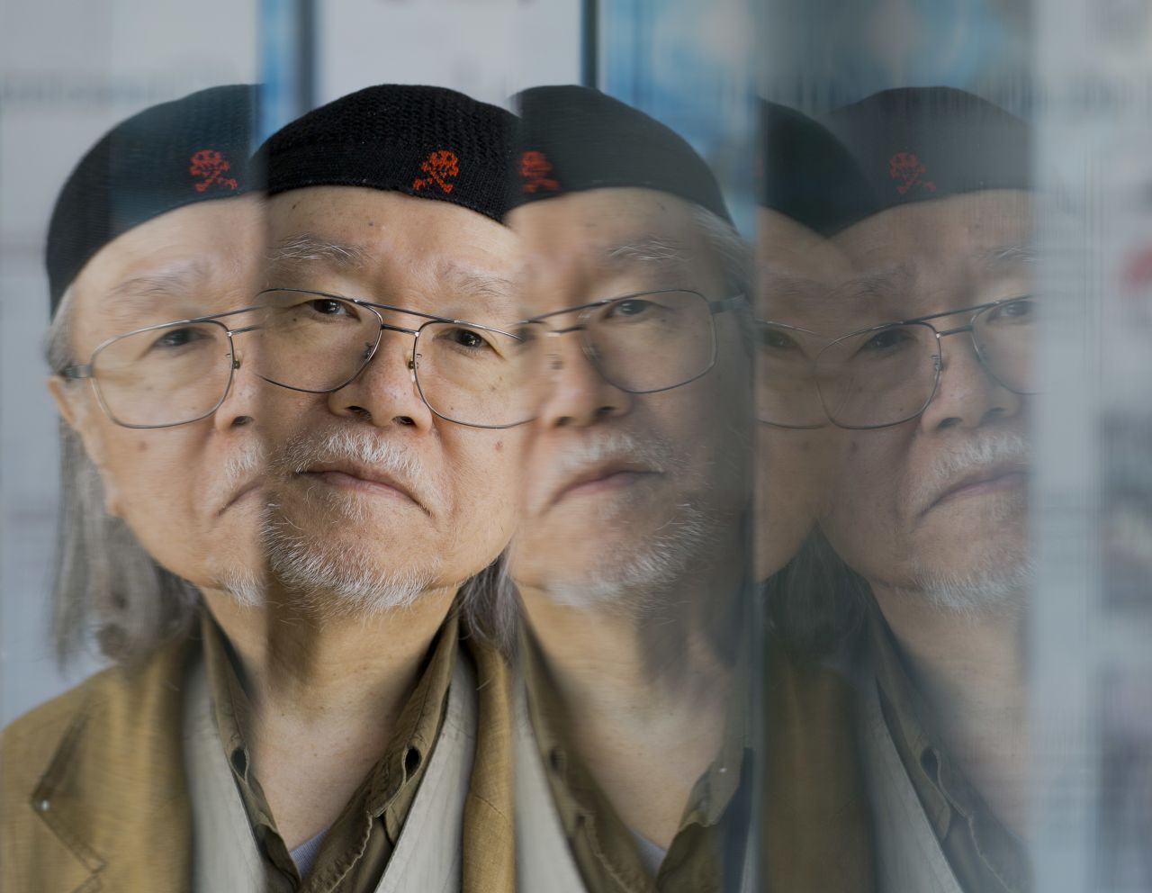 Manga artist Leiji Matsumoto is reflected on glass panels as he poses for portraits on September 3.