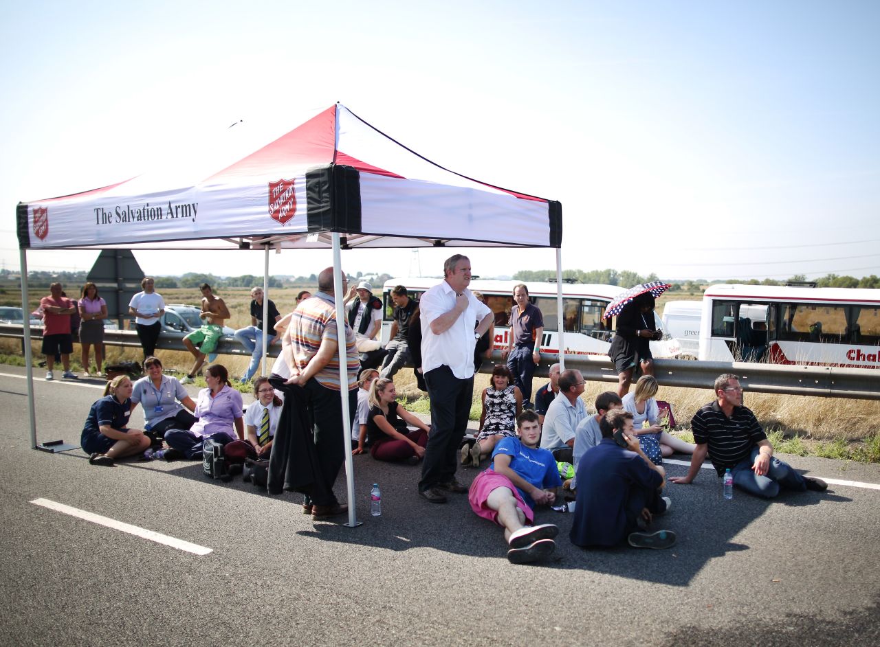 Drivers shelter from the sun under a tent provided by The Salvation Army as they wait to recover their vehicles.
