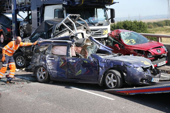 A vehicle recovery worker guides a car onto a trailer.