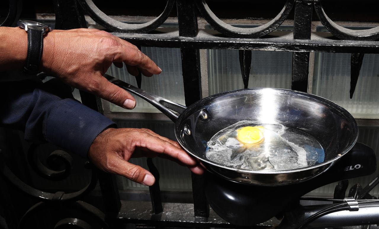 An egg is fried in a pan using heat from reflected sunlight off the surface of the Walkie Talkie tower in central London on September 4. The Walkie Talkie tower reflects sunlight at an intensity capable of melting parts of a car and has become an attraction in the city's financial district.