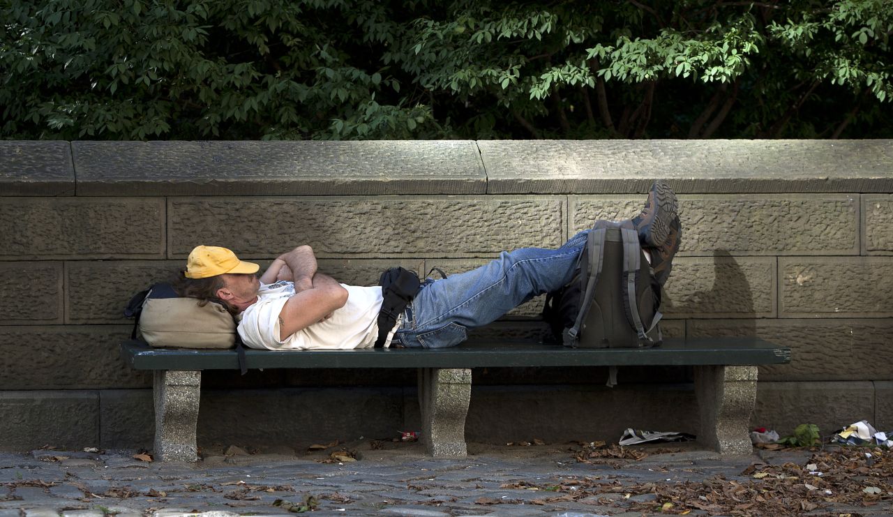 A man takes a nap on a park bench in the late afternoon sun along 5th Avenue at Central Park in New York on September 3.