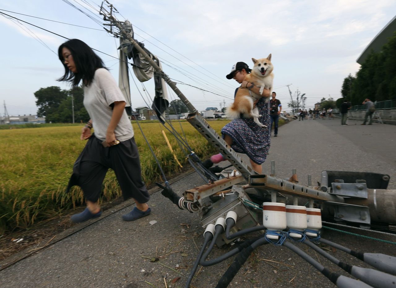 Residents walk over collapsed utility poles after a tornado struck Koshigaya, Saitama Prefecture, north of Tokyo, on September 2.