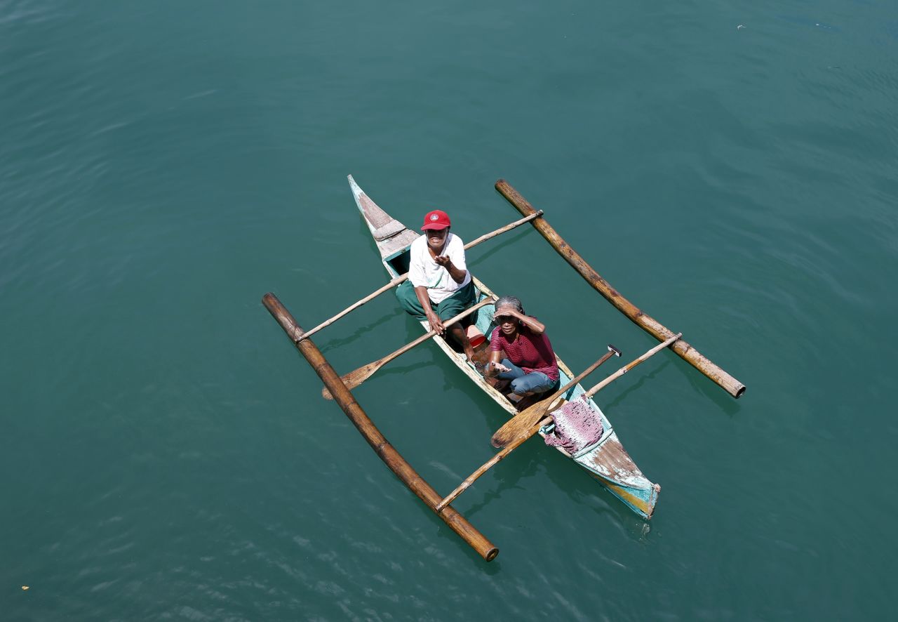 People aboard a locally made boat ask for money from passengers on a ferry at Dalahican port in Lucena City, south of Manila, Philippines, on September 2.
