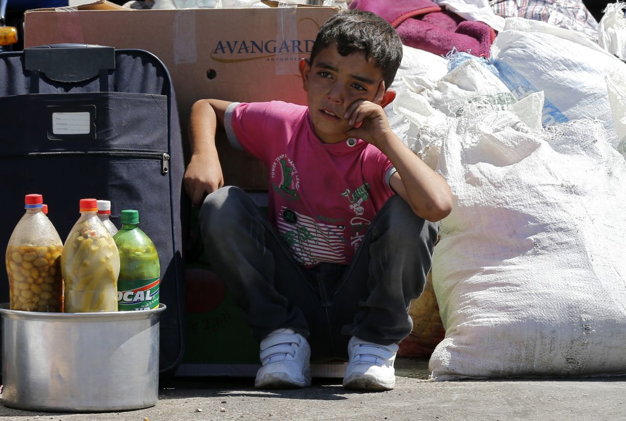 A Syrian boy sits beside his family's belongings in September 2013 as they wait for a vehicle to pick them up after entering Turkey.