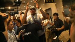 Security rushes away Dennis Rodman in Beijing after he is mobbed by reporters asking about his second trip to North Korea in a year.