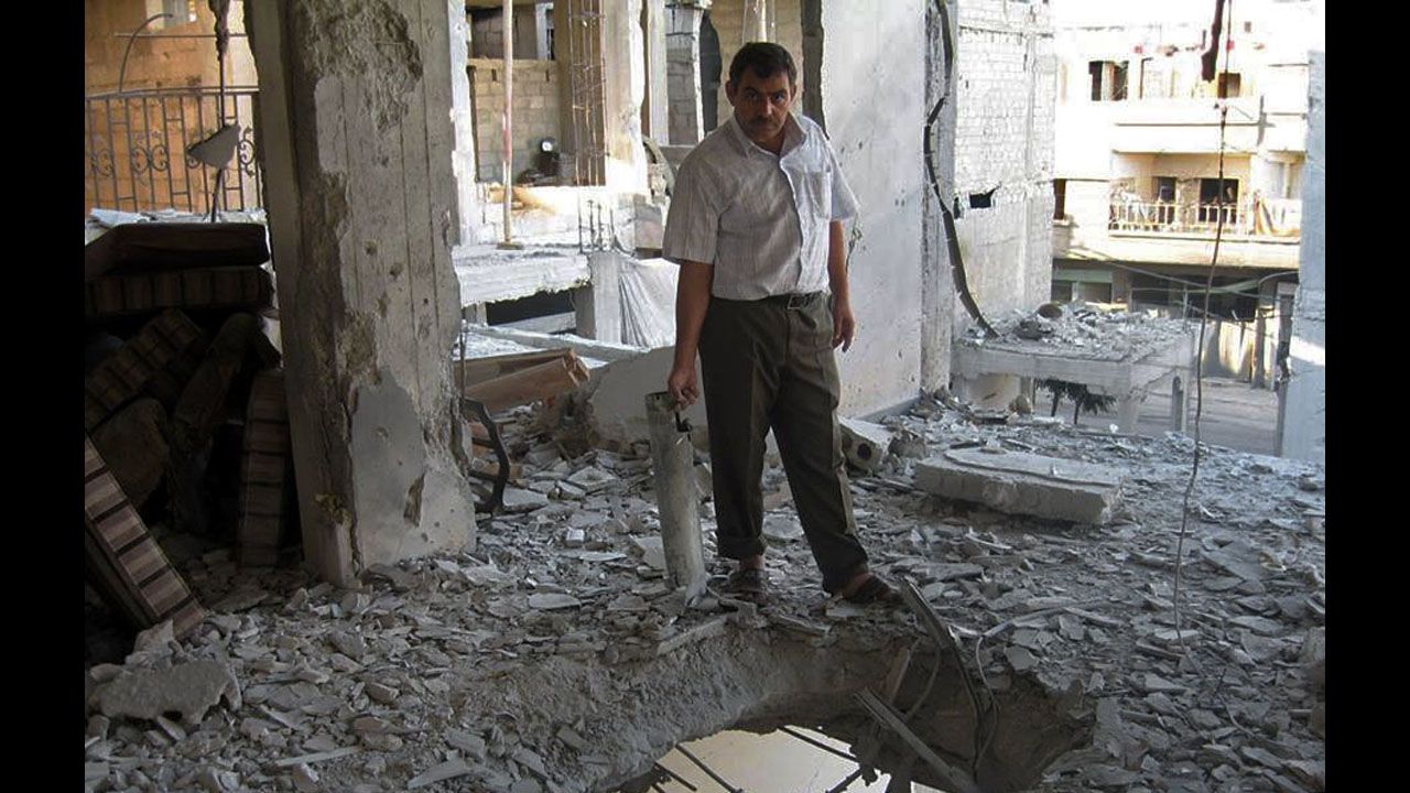 Un civil dentro de una casa muestra los daños causados por el intenso fuego de artillería en Arbeen, un suburbio de Damasco.