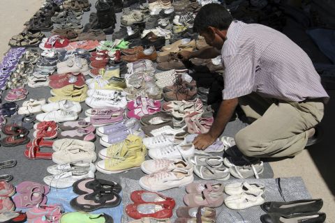 A Syrian refugee displays second-hand shoes for sale at the main market at the Zaatari refugee camp near Mafraq in September 2013.