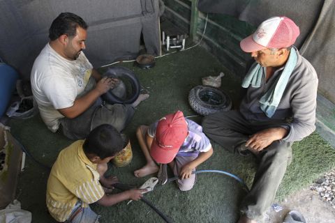 Syrian refugee workers fix cart wheels at their shop at the Zaatari refugee camp in September 2013.