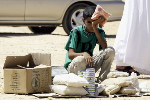 A young Syrian refugee boy sells canned tuna and other food items in the Zaatari refugee camp in September 2013.