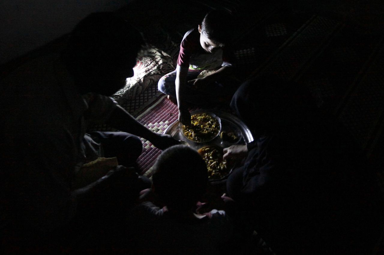 Issa eats dinner with his family inside the weapons factory.