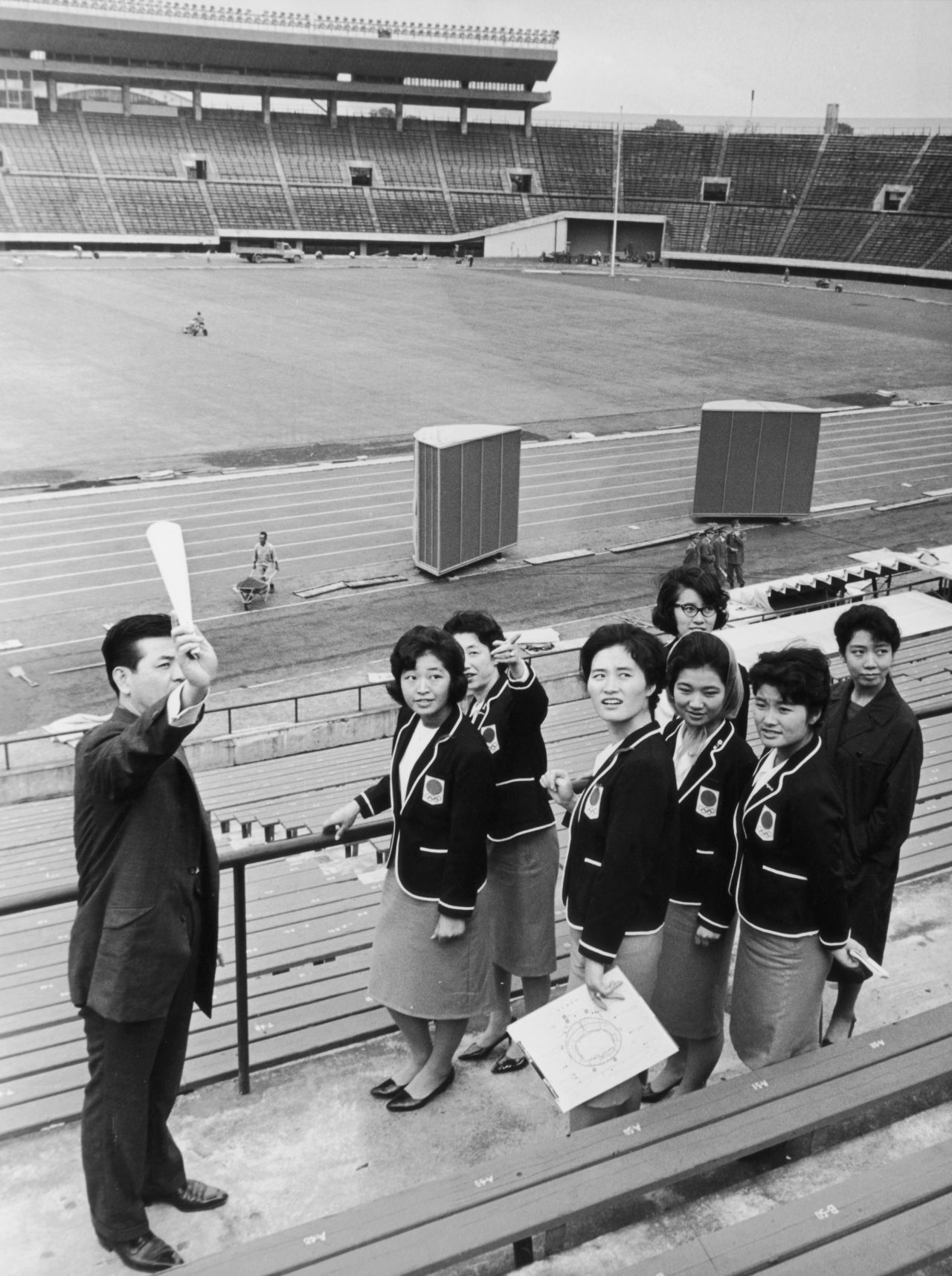 Olympic hostesses receive a briefing from an official at the main stadium in Tokyo, 1964.