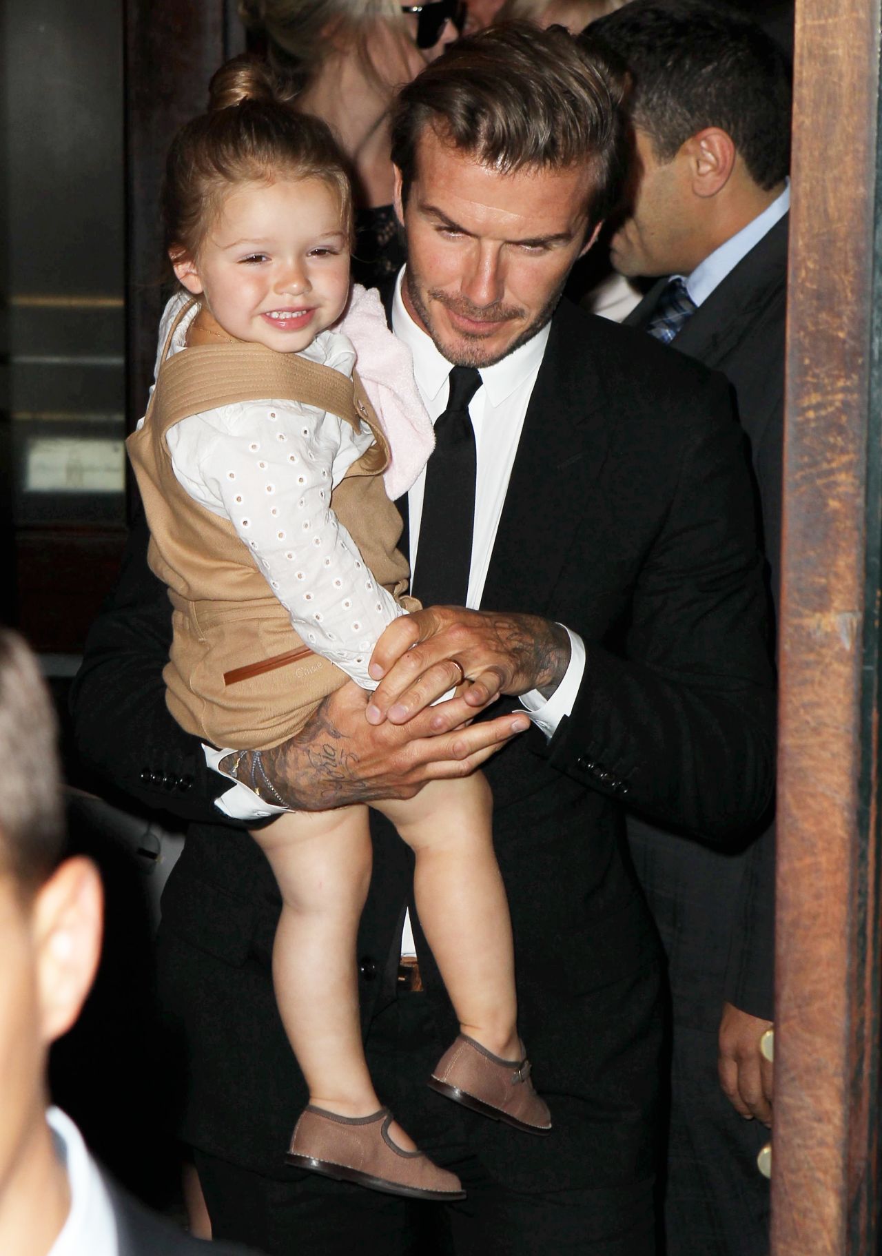 David Beckham carries smiling daughter Harper through the New York fashion week crowd on September 8.