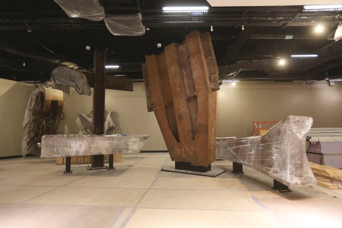 The "Cross," made of intersecting steel beams found in the rubble of 6 World Trade Center, and a fragment of a trident column, center, one of 84 that formed the exterior structure of each tower, are prepared for display.
