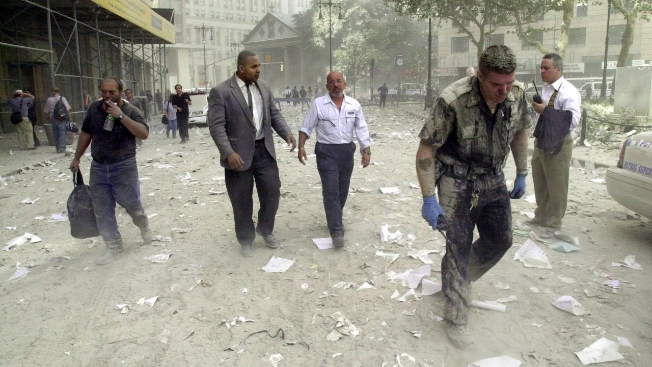 People walk in the debris-covered streets near the World Trade Center towers on September 11, 2001.