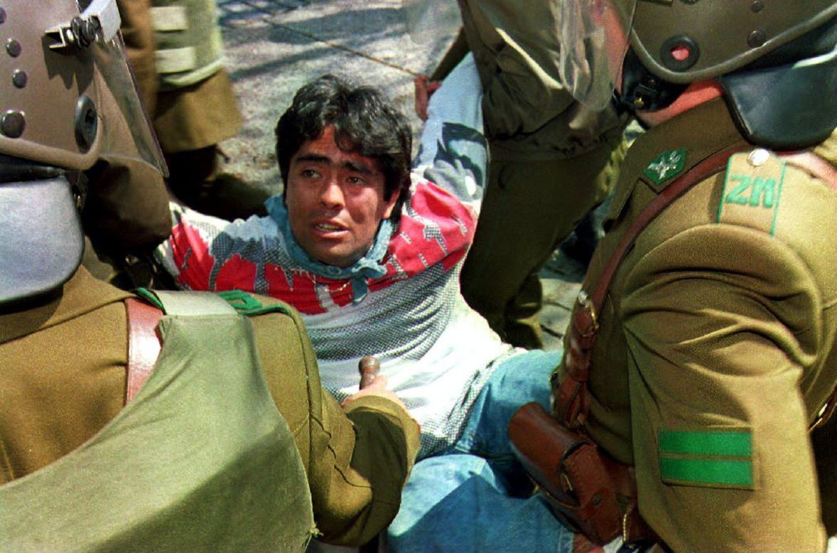 A man is arrested and carried by Chilean riot policemen as hundreds of students protest on September 11, 1993 in Santiago, Chile, during a march organized by leftists parties on the 20th anniversary of the military coup. Police stopped the marchers from reaching the La Moneda Presidential Palace.