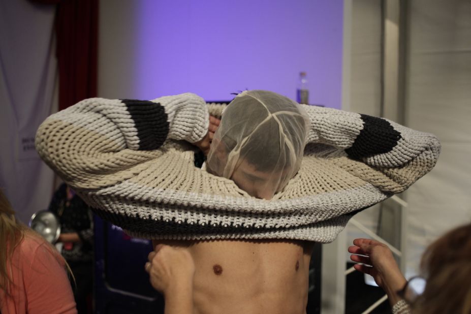 A model puts on a face net to protect his makeup during an outfit change at the Nautica show.