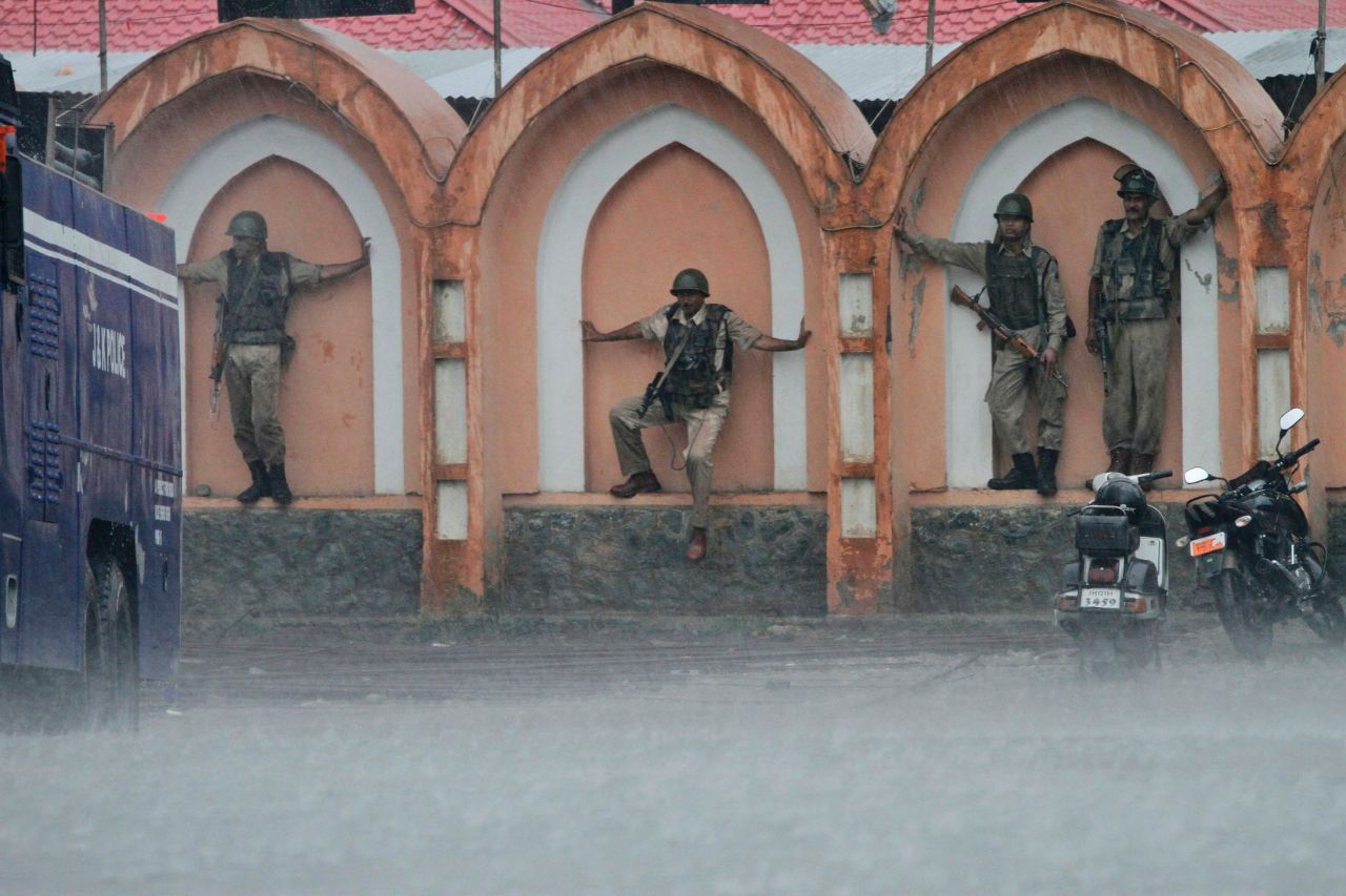 Indian paramilitary soldiers lean against the wall of a government building during a strike to protect themselves from the rain in Srinagar, India, on September 12. 