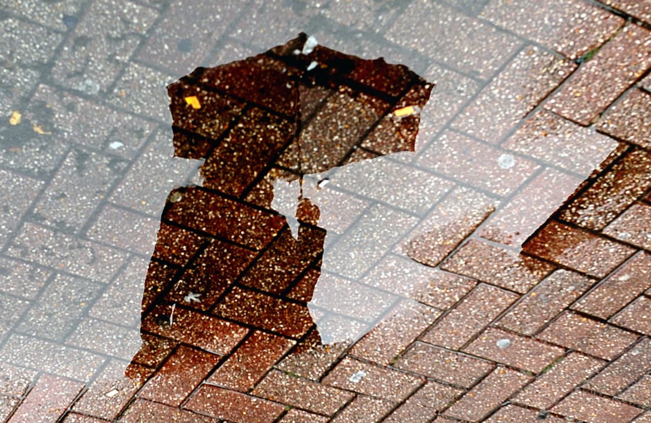 A person using an umbrella is reflected in a puddle on September 11 in Lille, France.