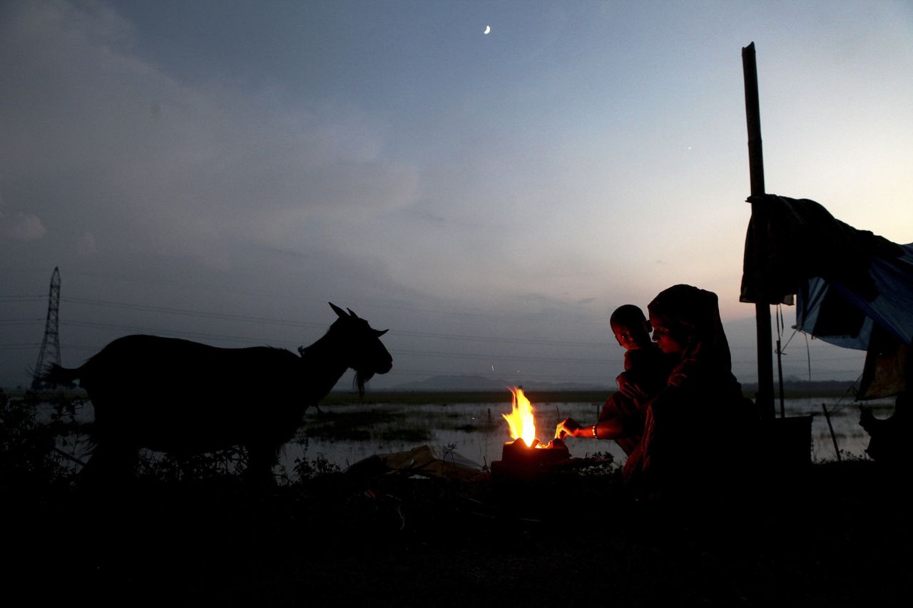 A woman holds her baby as she prepares food near a temporary shelter at the Burhaburhi village in Assam, India, on September 10. At least 10 districts of northeastern Assam state are affected due to the flooding of the Brahmaputra river, according to local news reports.