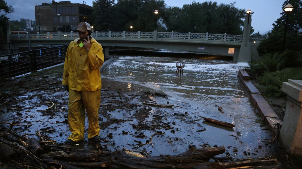 A city worker talks on his phone while surveying high water levels from Boulder Creek after flash flooding in downtown Boulder, Colorado, on September 12.