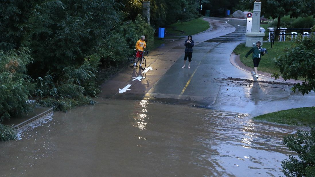 People stand at the edge of floodwaters in Boulder on September 12.