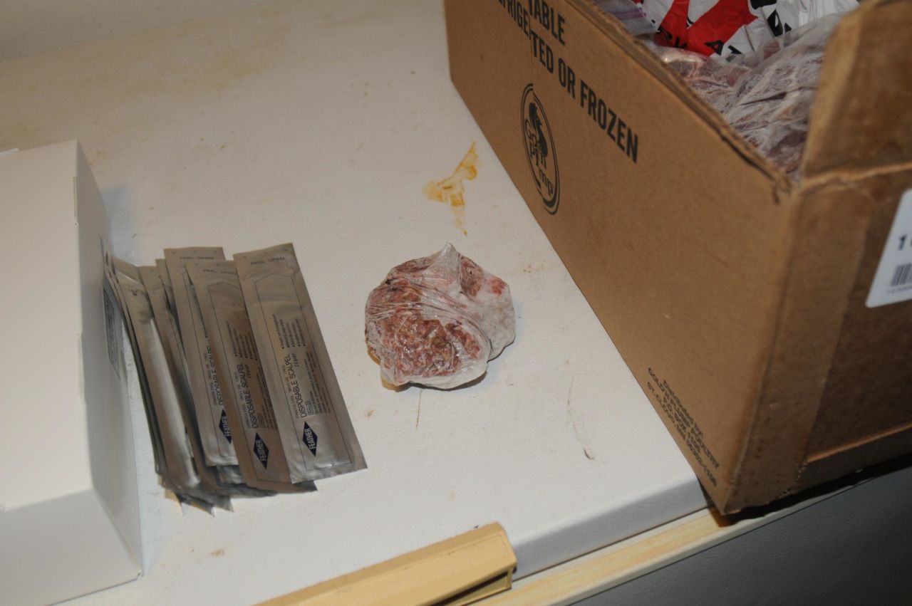 Jeringas descartables junto a un pedazo de pollo crudo.<br />
