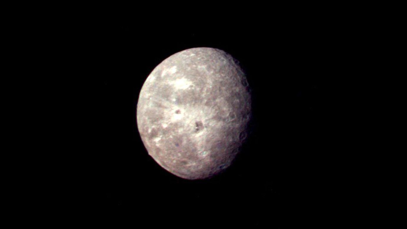 Oberon, Uranus' outermost moon, shows several impact craters on the moon's icy surface. 