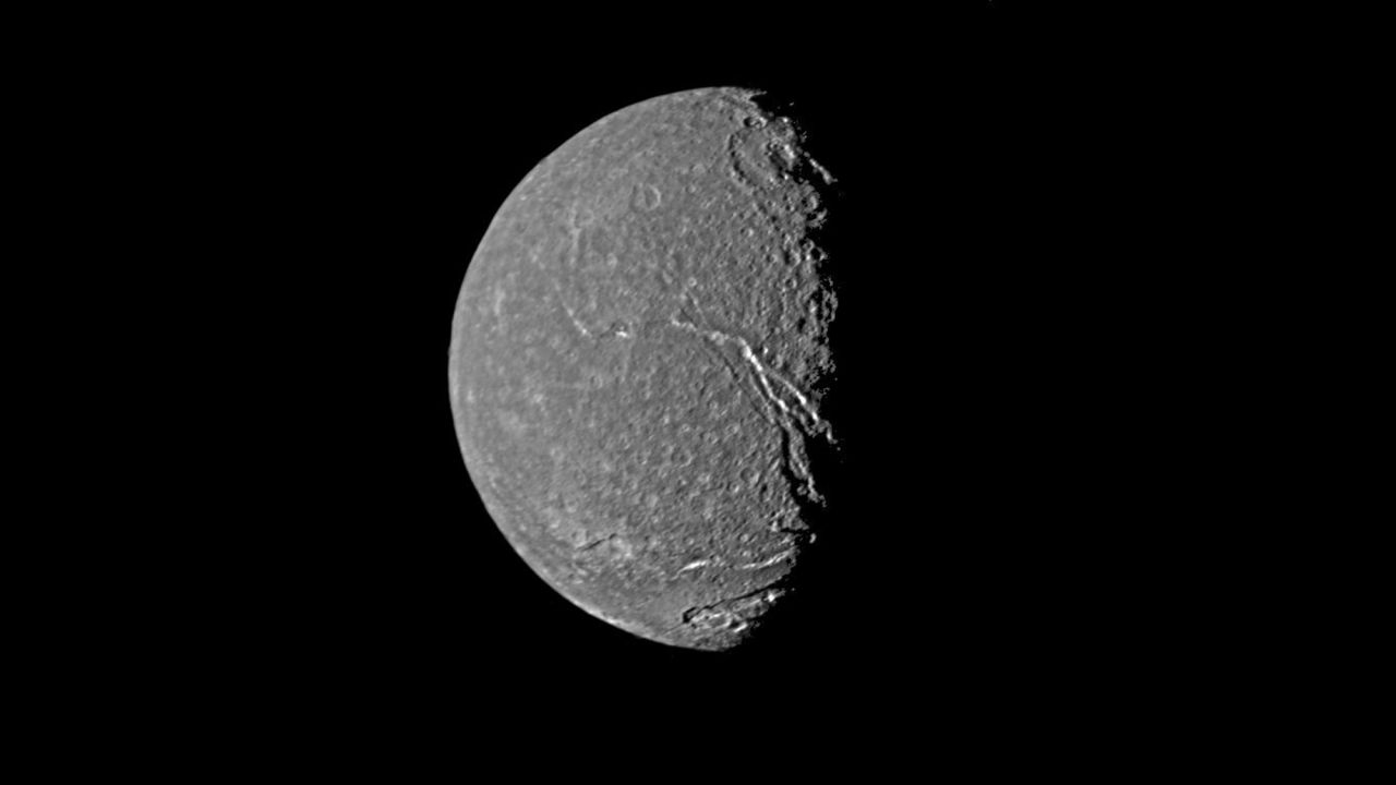 Uranus' moon Titania shows a crater-pocked surface as well as prominent fault valleys that stretch across the moon.