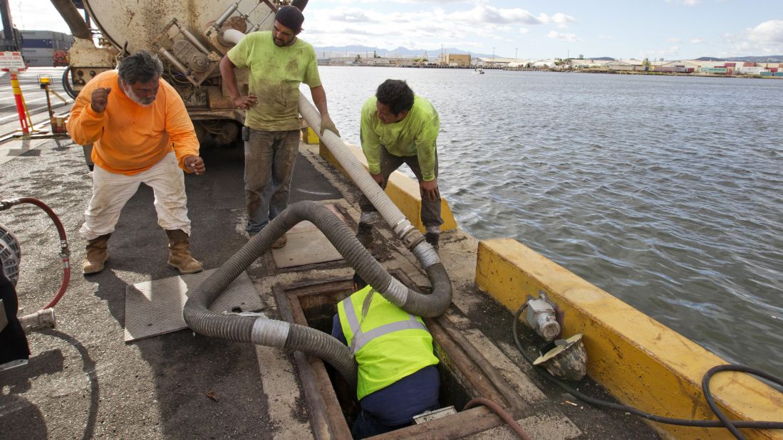 Workers from Pacific Environmental pump out the broken Matson pipeline, located under the neighboring Horizon shipyard dock in Honolulu, on September 11.