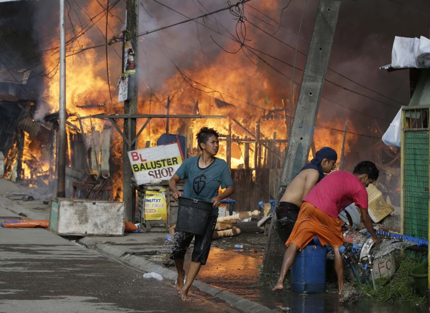 Residents try to put out fire that gutted several homes while government troopers continue their assault at Muslim rebels on September 12 in Zamboanga City.