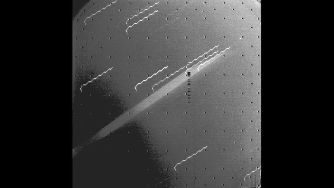 Voyager 1 captured the first evidence of a ring around the planet Jupiter. The multiple exposure of the extremely thin faint ring appears as a broad light band crossing the center of the picture. The background stars look like broken hairpins because of spacecraft motion during the 11-minute  exposure. The black dots are geometric calibration points in the camera. 