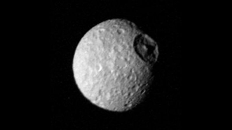 The cratered surface of Saturn's moon "Mimas" is seen in this image taken by Voyager 1 on November 12, 1980. Impact craters made by the infall of cosmic debris are shown; the largest is more than 100 kilometers (62 miles) in diameter and displays a prominent central peak.
