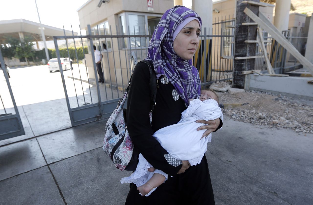 Una mujer siria lleva a su bebé a través de la frontera hacia Turquía en el puerto fronterizo de Cilvegozu en Reyhandi, Hatay, Turquía, el martes, 12 de septiembre. 