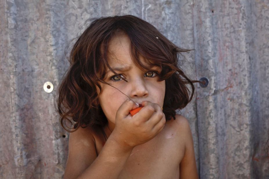 A Syrian girl eats a tomato at a temporary refugee camp in the eastern Lebanese town of al-Faour in September 2013.