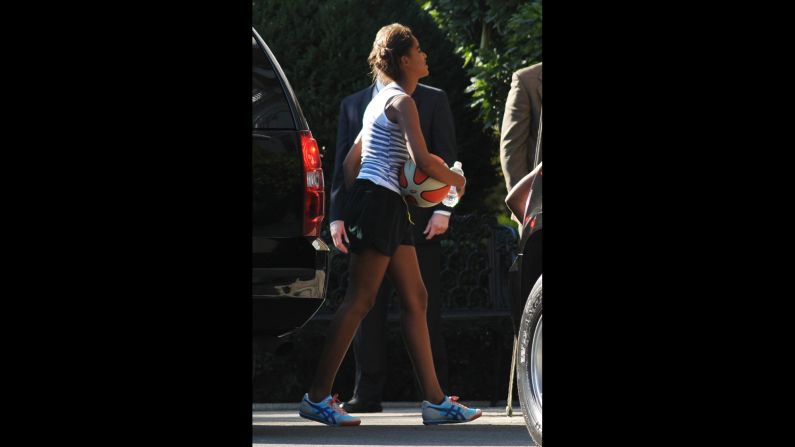 The Obamas' older daughter, Malia, walks from a SUV, water in hand, after returning from a game of basketball with her father and sister on September 18, 2010, at the White House.