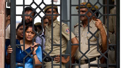Indian court staff and police officers watch demonstrators shout slogans after the sentencing at the Saket courthouse in New Delhi.
