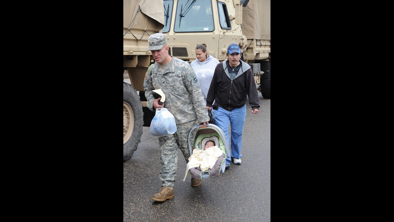 Colorado Army National Guard Sgt. David Wilson carries Ezra Villa while escorting Thomas Walter and Melinda Villa to the flood evacuation area in Lyons on September 13.