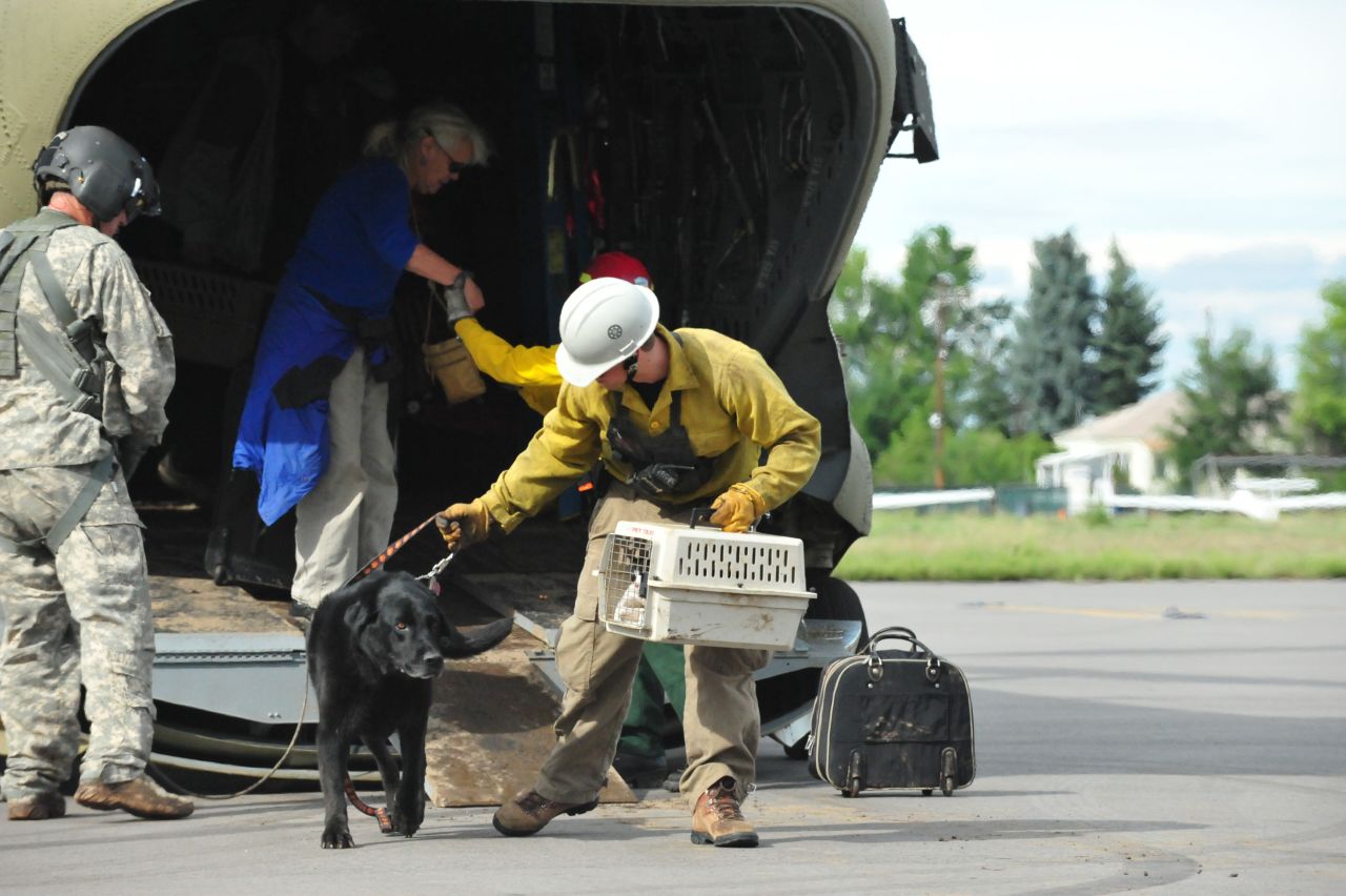 Guardsmen help residents and their pets off a Colorado National Guard Chinook helicopter at the Boulder Municipal Airport on September 13.