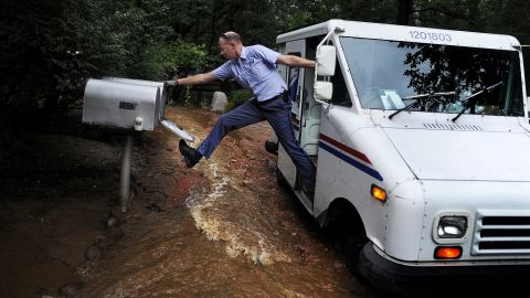 Dave Jackson closes a mailbox with his foot after delivering the mail to a home surrounded by water from the flooded Cheyenne Creek in Colorado Springs, Colorado, on Friday, September 13.