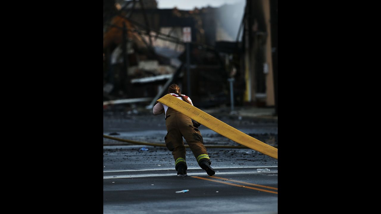 A firefighter pulls a fire hose  on September 13. About 100 firefighters were still handling hot spots Friday and mopping up, said Ocean County Fire Administrator Brian Gabriel.