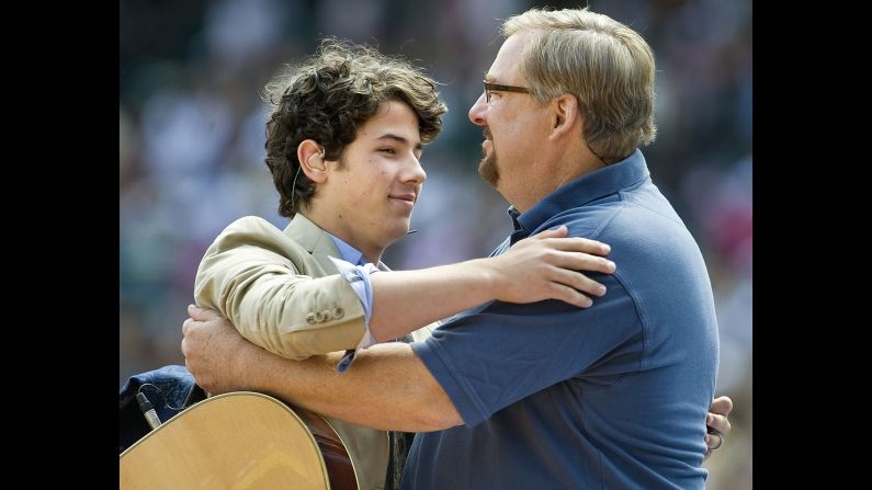 Nick Jonas of the Jonas Brothers embraces Warren after a short performance with his brothers during the church's 30th anniversary Easter services at Angel Stadium in Anaheim, California, on April 4, 2010.