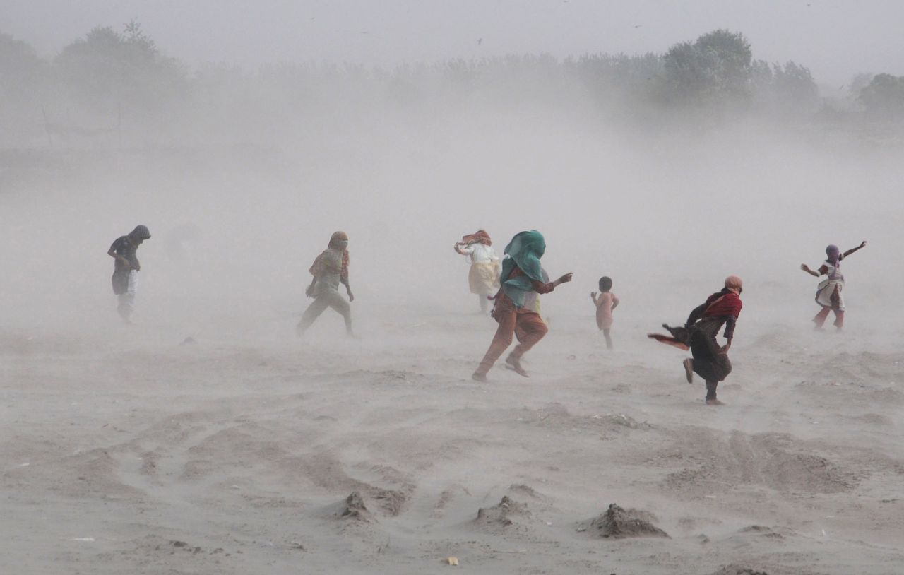 People walk through a storm near the Ravi River in Lahore, Pakistan, on Sunday, September 15. Click through to see more photos of weather around the world.