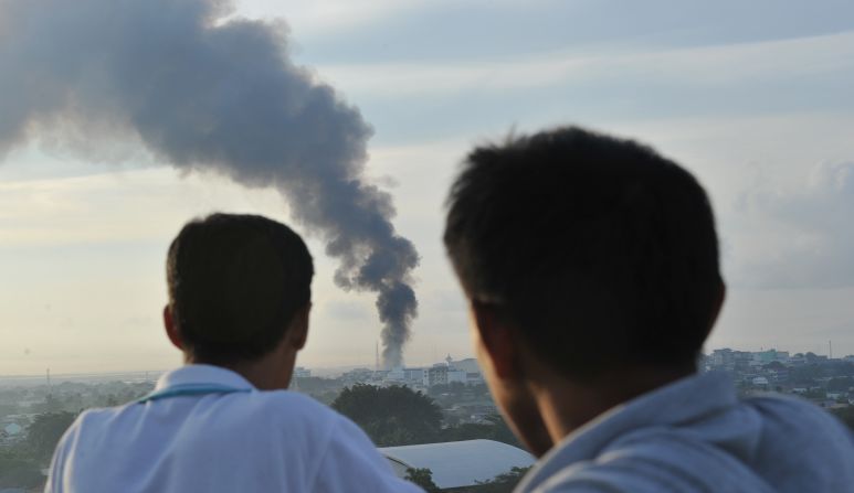 Two men watch as smoke billows from burning houses as firefight between government troops and Muslim rebels rages in Zamboanga City, on September 16. Sporadic clashes continued as soldiers moved to clear Moro National Liberation Front (MNLF) gunmen from coastal neighbourhoods after a ceasefire plan collapsed. 